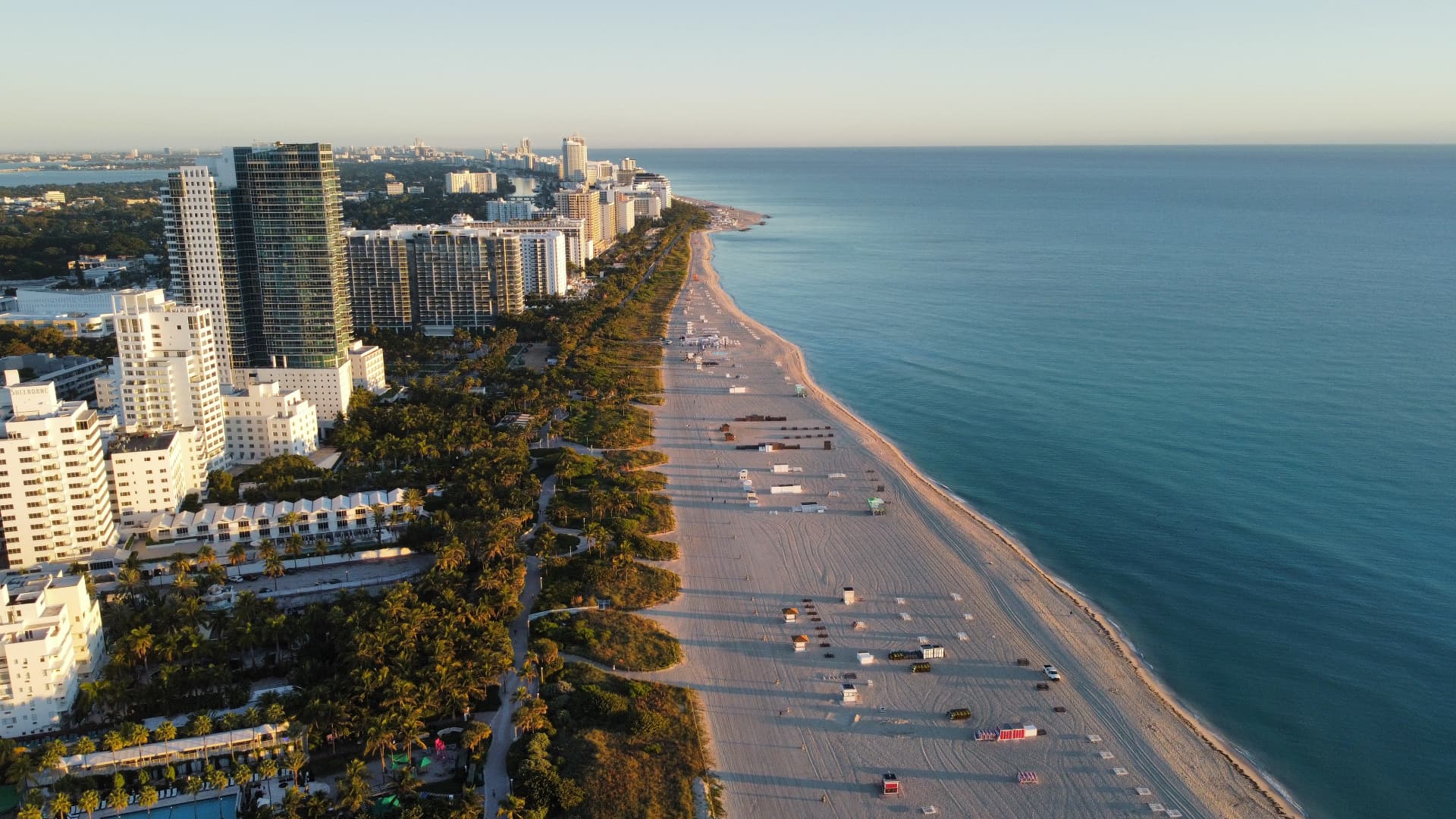 Aerial view along the Miami Beach coastline with the city skyline at golden hour