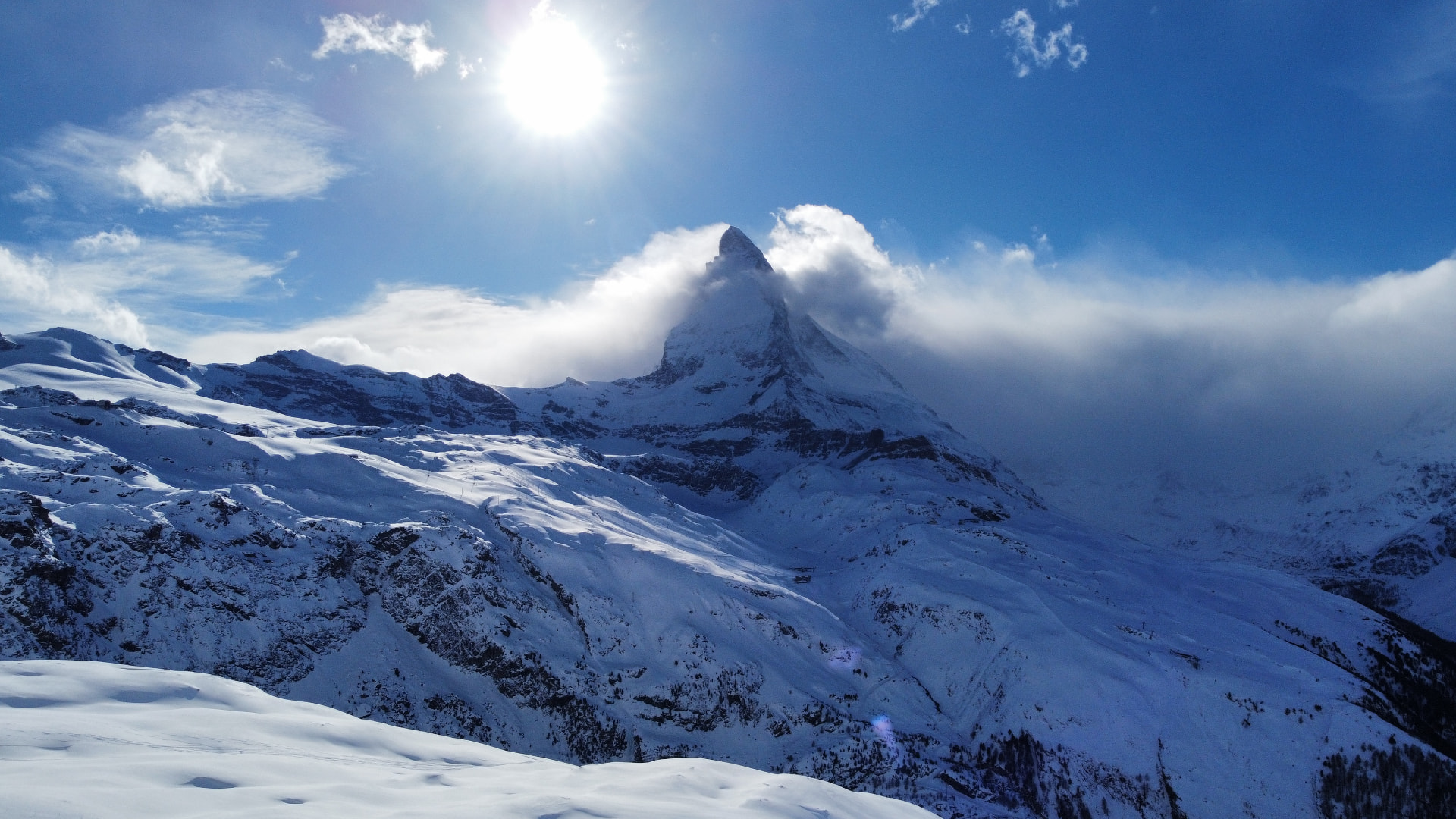 The Matterhorn emerging from the clouds above snow-covered slopes — aerial view, Zermatt